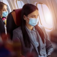 Femeie în avion care poartă mască de protecție