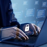 Bărbat în costum care scrie la un laptop, într-o încăpere întunecată.