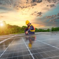 Un muncitor montează panouri fotovoltaice pe o casă.